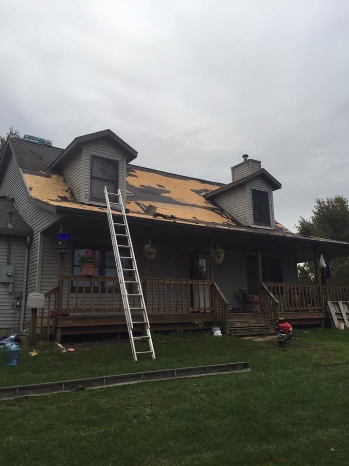 Full roof tear-off in progress exposing decking on cape-style home