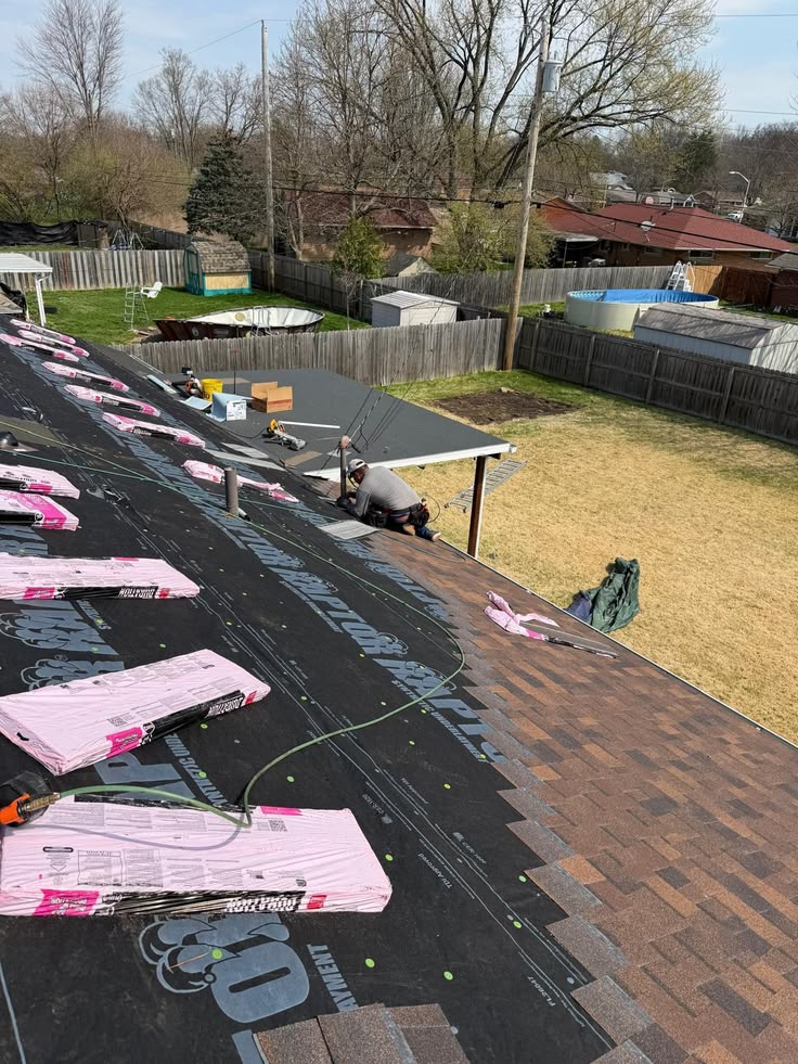 Shingle installation in progress with underlayment and bundles staged on roof